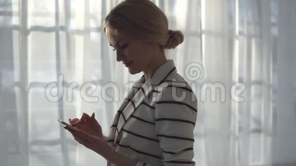 穿着条纹夹克的年轻女人窗户背景上有电话视频的预览图