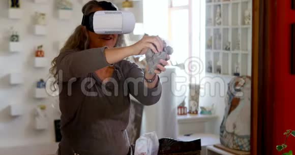 成熟的女性陶工在使用虚拟现实耳机4k的同时塑造粘土视频的预览图