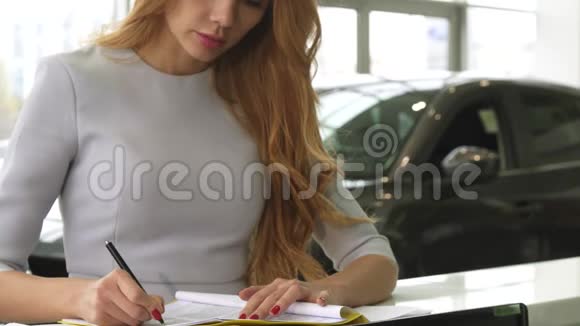 一名女性顾客在经销商展厅签售文件的镜头视频的预览图