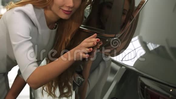 一个女人在经销商店里查看一辆新车上的汽车油漆视频的预览图