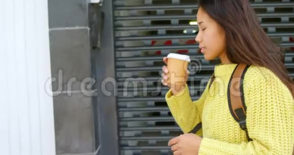 少女在人行道上散步时喝咖啡视频的预览图