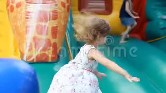 小女孩跳在蹦床上为孩子们在操场上玩耍儿童游戏视频的预览图