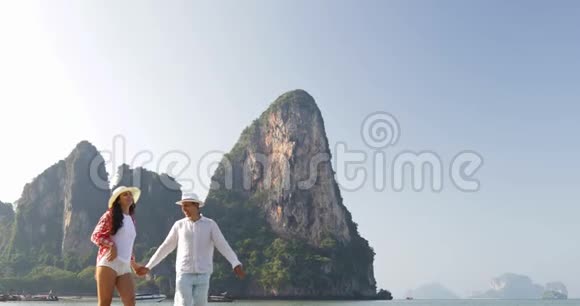 情侣在沙滩上散步牵着手年轻快乐的男人和女人在山上旅游度假视频的预览图