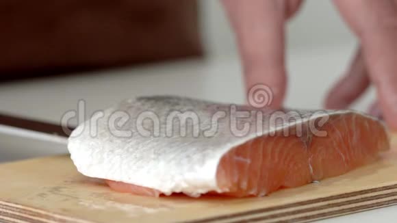 在木板上缓慢切割一块鲑鱼的过程视频的预览图