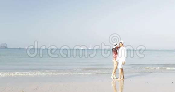 情侣在沙滩上亲吻男人和女人在海上度假时拥抱年轻的快乐游客视频的预览图