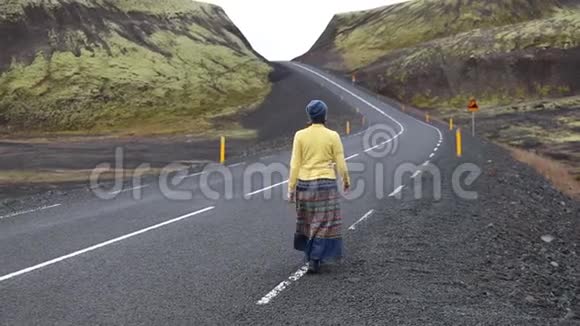 一个年轻的女人在一个美丽的山湖的背景下走在山里的路上她快乐快乐欣赏视频的预览图