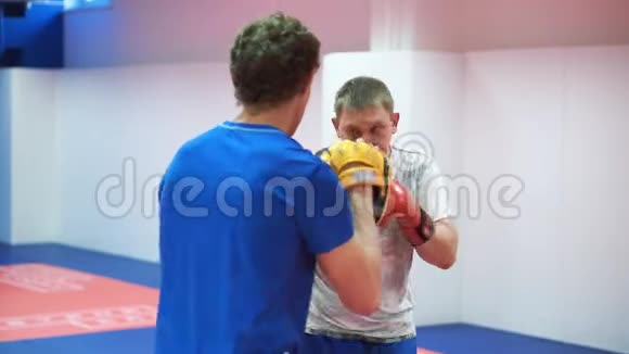 在拳击馆训练一名中年运动员和他的教练戴着拳击手套罢工视频的预览图