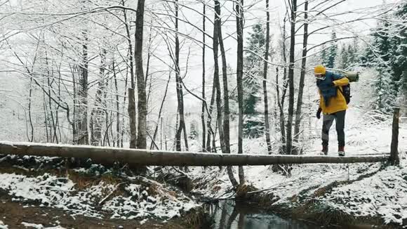 冬天被白雪覆盖的山脉一个穿着背包的徒步旅行者正穿过小溪视频的预览图