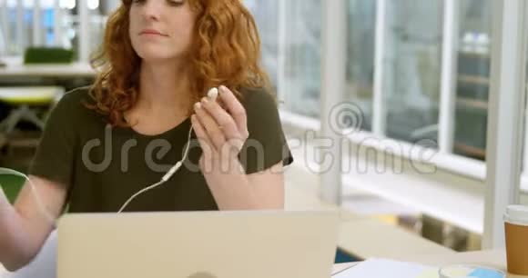 女商人在书桌旁听手机音乐视频的预览图