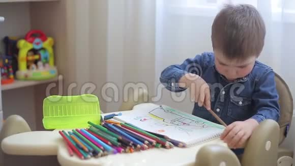 一个小孩子学会用彩色铅笔在纸上画画视频的预览图