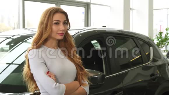 站在汽车经销店的年轻美女对着镜头微笑视频的预览图
