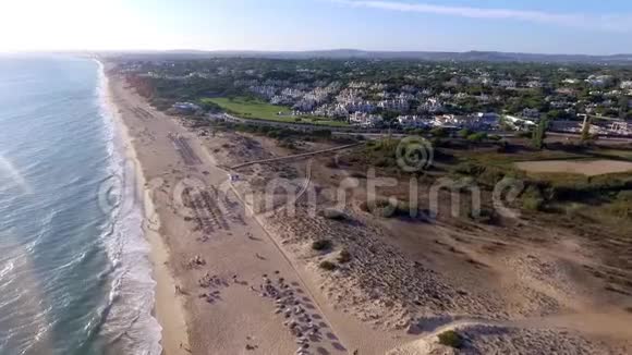 海滩阳光明媚的一天海滩上有海岸水海洋海洋蓝色的空中视频有雨伞和松林酒店度假者在海滩上视频的预览图