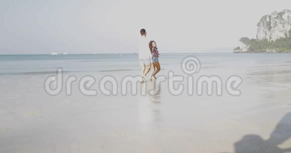 情侣在沙滩上奔跑手牵手年轻的快乐游客在爱中拥抱度假视频的预览图
