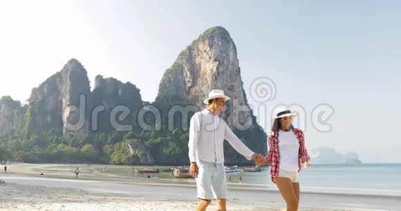 情侣在沙滩上散步牵手谈情说爱的年轻人和女人在度假拥抱游客视频的预览图