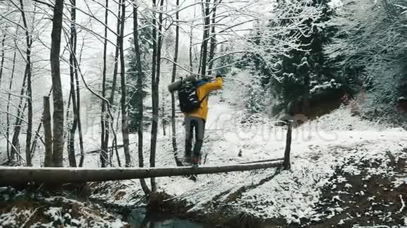 冬天被白雪覆盖的山脉一个穿着背包的徒步旅行者正穿过小溪视频的预览图