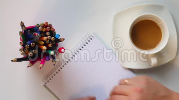 一个男人从桌子上的杯子里喝咖啡然后他拿起一支笔思考在笔记本上写什么不时地h视频的预览图