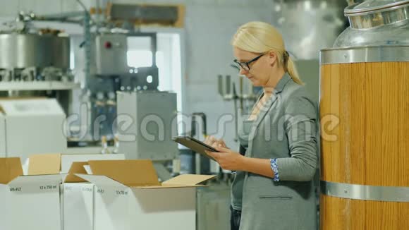 一位带着药片的妇女在一家生产酒精饮料的工厂工作她就在盒子旁边视频的预览图