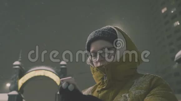 女人在冬天晚上使用智能手机视频的预览图