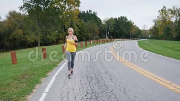 一个女人在一个漂亮整洁的公园里沿着小径慢跑前景斯特朗姆视频的预览图