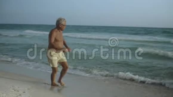 快乐的白种人美国老年男性享受他的户外生活方式跳舞海滩美国4k视频的预览图