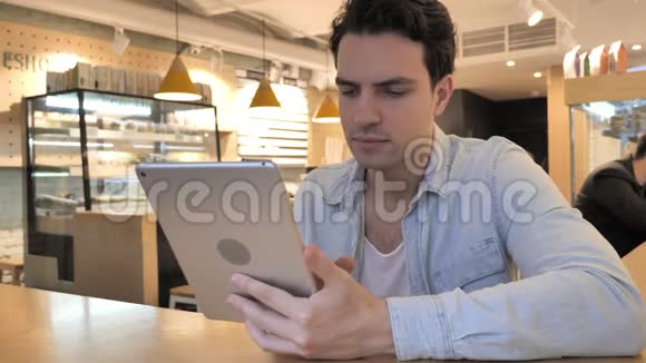 咖啡屋使用平板电脑的临时青年视频的预览图
