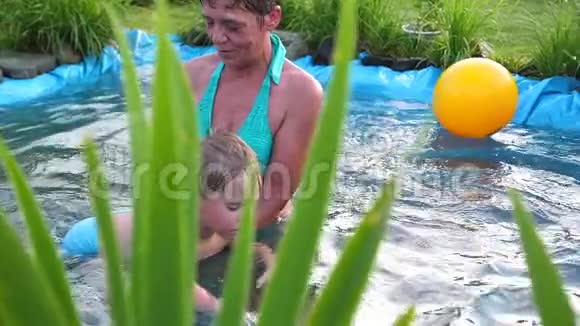在炎热的夏天一家人在一个小湖里游泳奶奶学游小孩子花园花草视频的预览图