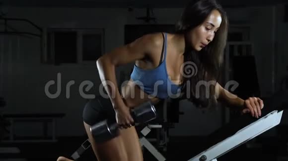 女人在健身房训练女运动员用哑铃训练他的二头肌视频的预览图