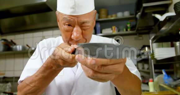 男厨师在厨房里看刀视频的预览图