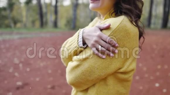 一个穿着黄色毛衣的年轻女子在秋天公园散步黑发女人在寒冷的森林里晒太阳恋爱中的女人视频的预览图