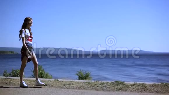 夏天一个年轻漂亮的女孩在海边喝一瓶水视频的预览图