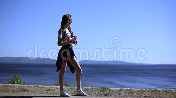 夏天一个年轻漂亮的女孩在海边喝一瓶水视频的预览图