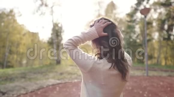 一个穿毛衣的年轻女子在秋天公园散步黑发女人在寒冷的森林里晒太阳公园里的浪漫女人视频的预览图