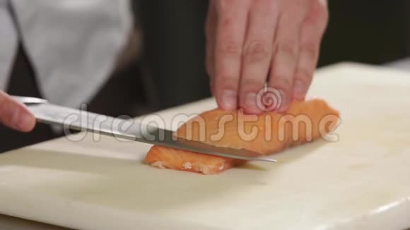 在厨师手近距离拍摄男人把一条鳟鱼切成两半视频的预览图