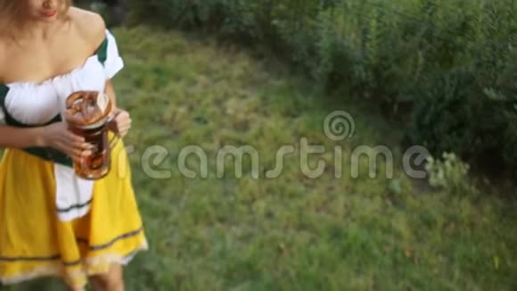 德国音乐节啤酒节女服务员一个穿着巴伐利亚西装的女孩走在草地上拿着啤酒视频的预览图
