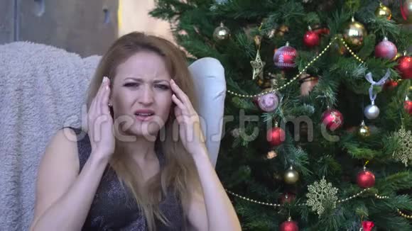 在圣诞树背景上头痛的被压着的女人室内悲伤的年轻女子视频的预览图