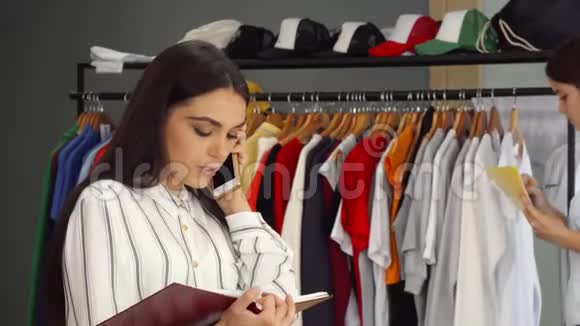 漂亮的女店员在打电话在服装店工作视频的预览图