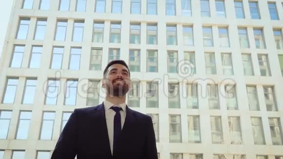 幸福的商人在城市里走来走去成功而自信的男人在现代建筑的背景下视频的预览图