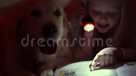 与宠物的快乐生活孩子们晚上和他们的大狗在被子下看书视频的预览图