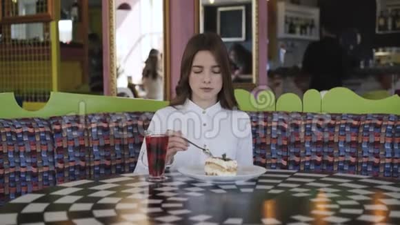 漂亮的女孩喝果汁在咖啡馆吃美味的甜点视频的预览图
