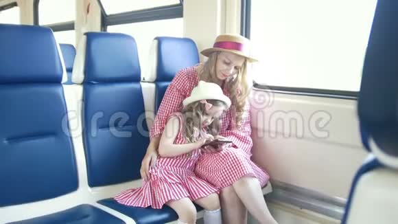年轻的白种人妈妈和女儿抱着火车用手机视频的预览图