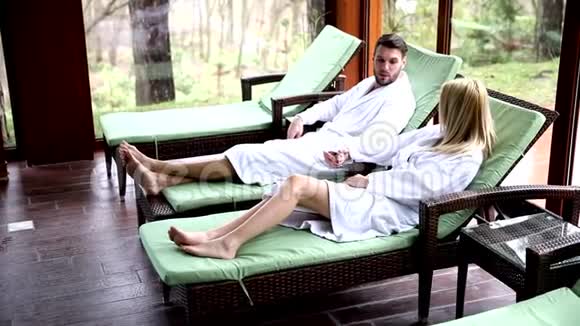年轻夫妇坐在室内游泳池旁的躺椅上视频的预览图
