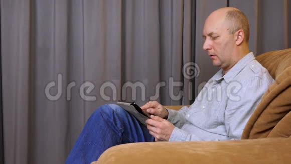 白人用手指在平板电脑上写字男人坐在扶手椅上视频的预览图