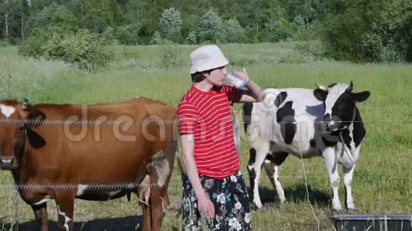 十几岁的孩子站在牧场上喝着新鲜牛奶视频的预览图