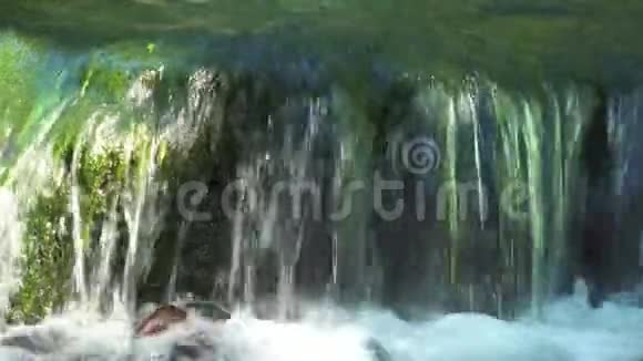 从瀑布流出来的水流在河中的石头上丛林中的高山瀑布视频的预览图