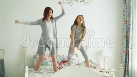 有趣的小女孩和她爱的母亲一起玩跳舞现代风格一起跳在床上早上在家视频的预览图