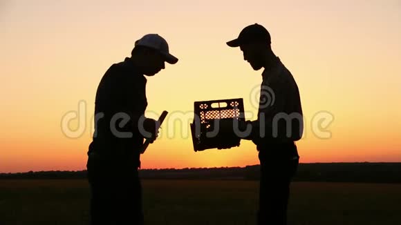 两个农民在日落时交谈在日落的时候侧视图视频的预览图