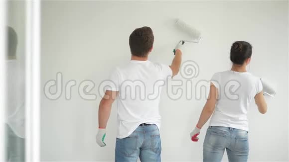 幸福夫妇一起修公寓的后景年轻的妻子和丈夫用白色油漆粉刷墙壁视频的预览图