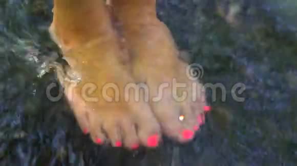 穿着粉色脚甲的女孩站在河边脚在水里视频的预览图