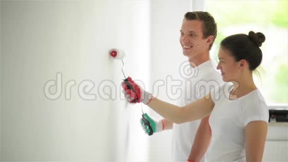 幸福的微笑情侣在他们的客厅用白色油漆粉刷墙壁的侧面视图女人与男人视频的预览图