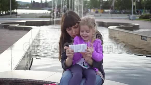 家庭母女在公园阴天玩智能手机视频的预览图